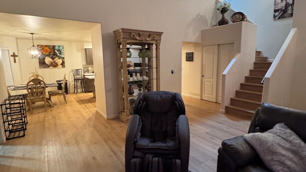 Un vaste espace de vie comprenant un fauteuil de massage, un canapé et, au fond, un coin repas.