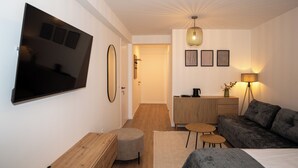 Un salon moderne avec un téléviseur à écran plat, un canapé, une table basse et une lampe.