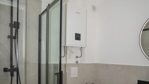 Une salle de bain moderne avec une douche à parois de verre, des toilettes blanches et un lavabo noir.