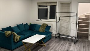 A modern living room with a teal sofa, a white coffee table, and a radiator.