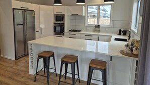 A modern kitchen with white cabinetry, stainless steel appliances, and a large island with bar stools.