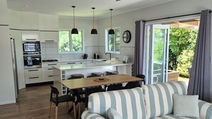 A modern kitchen with a dining area, a sofa, and a ceiling fan.