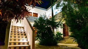 A staircase with patterned tiles leading to a building entrance, surrounded by greenery. - Hotel tropical casa blanca  (Playa del Carmen)