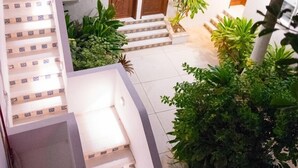 A multi-level building with a staircase leading to a covered outdoor area with plants and a wooden door. - Hotel tropical casa blanca  (Playa del Carmen)