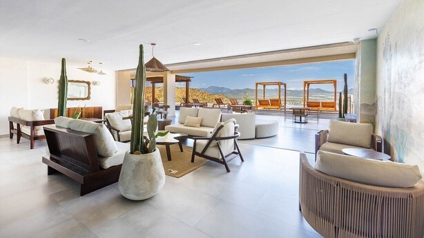 Amplia sala de estar con un gran ventanal que ofrece vistas al paisaje desértico. Hay varias opciones de asientos, incluyendo sofás y sillones.
