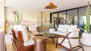 Una sala de estar moderna con un ventanal grande, una planta de cactus y un mural de fauna del desierto.