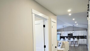 A modern kitchen with white cabinets, a microwave, and a dining area with a white table and chairs.