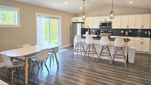 A modern kitchen with white cabinets, a black countertop, and a dining area with a white table and chairs.