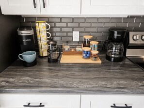 A kitchen with a coffee maker, a mug, a coffee pot, and storage containers. - Minutes to Charlottetown - Three Bedroom, King Beds, Family friendly. (Stratford)