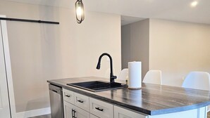 A modern kitchen with a central island, white cabinetry, and a black faucet.