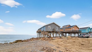 A coastal property with a pier extending into the water, featuring multiple houses and a truck parked nearby.