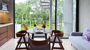 Ein Essbereich mit Tisch für vier Personen, einer Wendeltreppe und einem Balkon mit Blick auf Grünflächen.