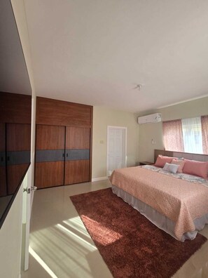 A bedroom with a bed, a wardrobe, and a window with curtains. - A Rejuvenating & Relaxing Retreat overlooking Ocho Rios. (Ocho Rios)
