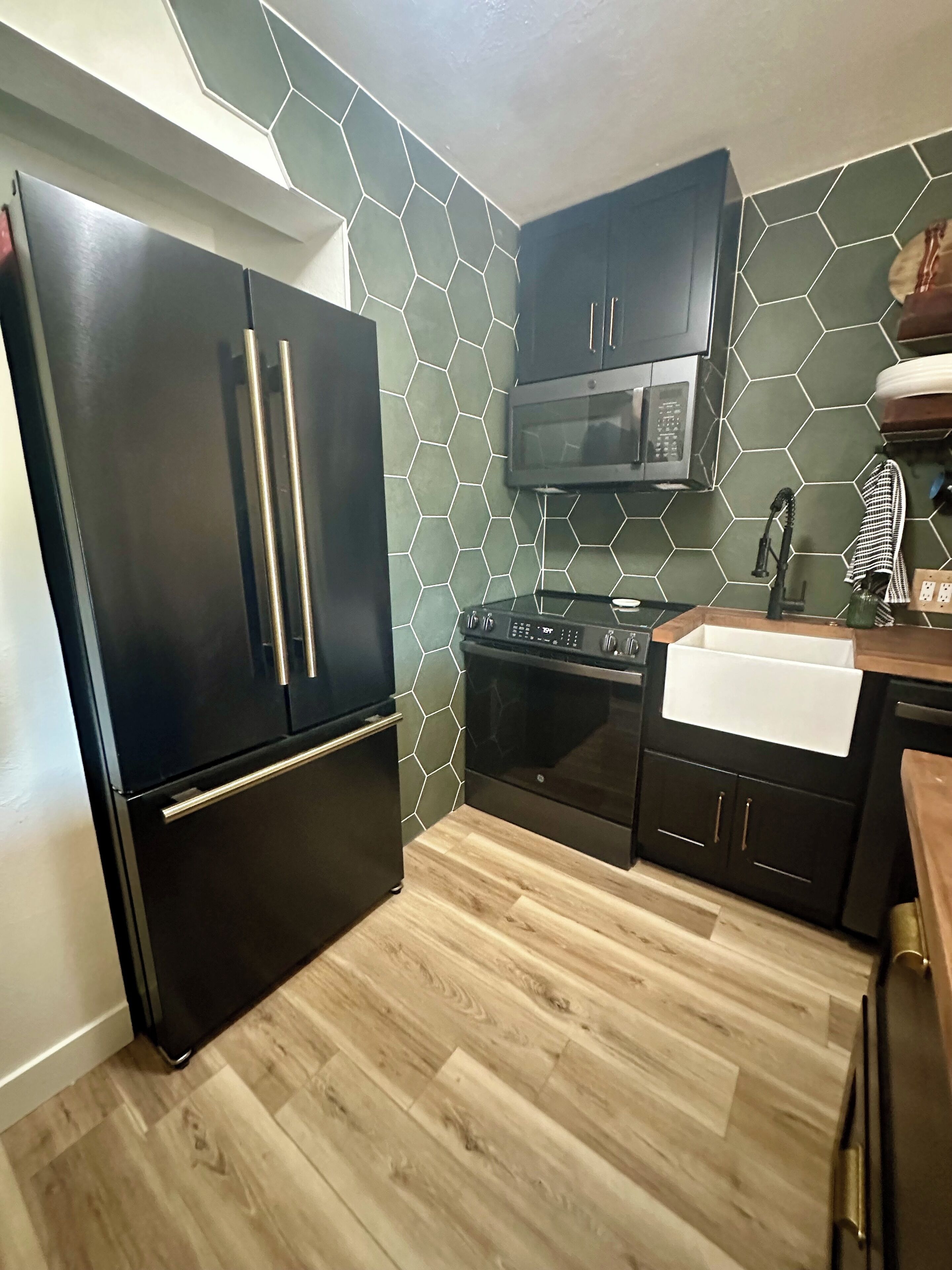 Una cocina compacta con un refrigerador negro, un microondas y una estufa.