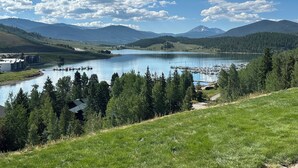 Näkymä järvelle, jossa on venesatama, metsäisiä kukkuloita ja kirkas taivas.