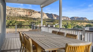 A wooden deck with a table and chairs, overlooking a mountainous landscape. - East Zion Modern Farmhouse, Sleeps 14, Hot Tub, Fire Pit & Chef Kitchen (Orderville)