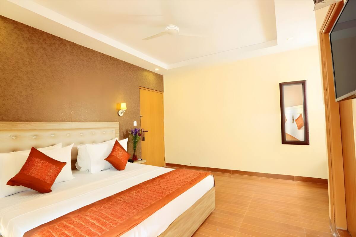 A hotel room with a large bed, a flat-screen TV, and a ceiling fan.