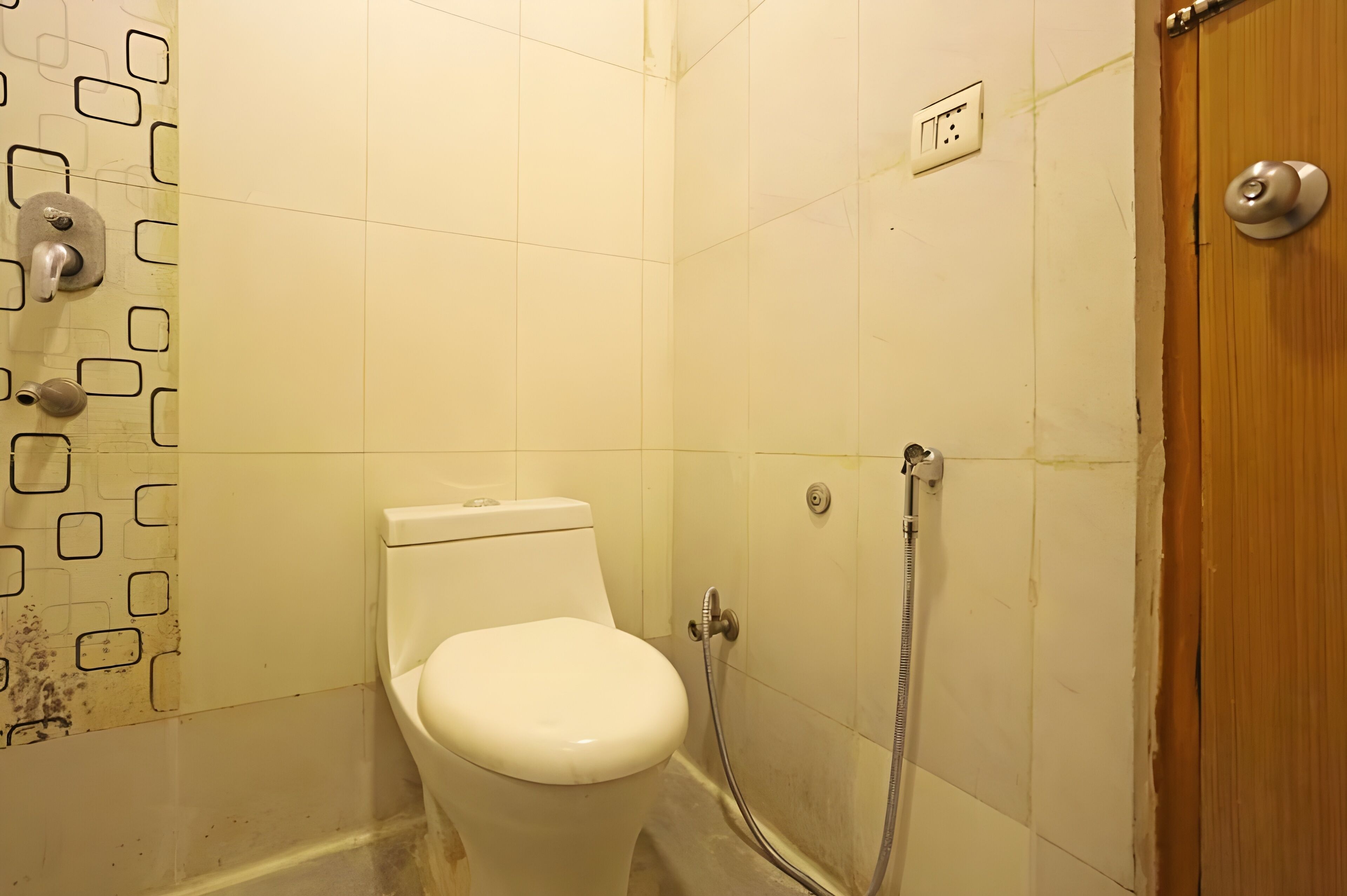A small, clean bathroom with a toilet, a shower, and a wooden door.