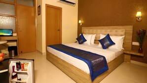 Una camera d'albergo con un letto, una scrivania, una televisione e un minibar.