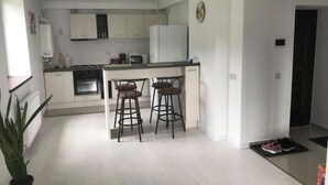 A modern kitchen with white cabinets, a central island with stools, a stove, and a microwave.