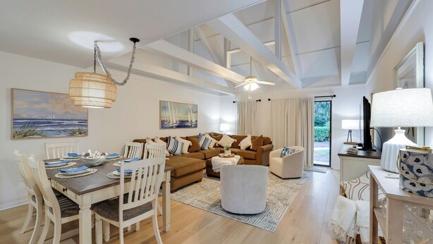 A spacious living area with a dining table, sofas, and a large window offering a view of the outdoors. - Hilton Head Retreat | Gated Villa, Pets OK (Hilton Head Island)