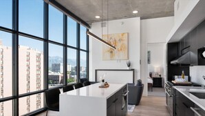 A modern kitchen with large windows, a central island, and a view of the city. - Luxury 2BR 2BA Penthouse-Pool, Gym, Pkg, Views! (Salt Lake City)