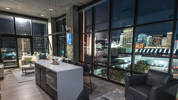A modern kitchen with a central island, large windows with city views, and a seating area with leather chairs. - Luxury 2BR 2BA Penthouse-Pool, Gym, Pkg, Views! (Salt Lake City)