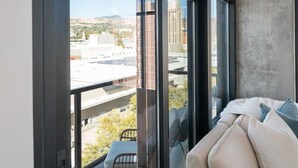 A modern room with large windows, a balcony, and a sofa with cushions. - Luxury 2BR 2BA Penthouse-Pool, Gym, Pkg, Views! (Salt Lake City)