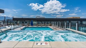 A rooftop pool with a hot tub, lounge chairs, and a glass-enclosed terrace with a mountain view. - Luxury 2BR 2BA Penthouse-Pool, Gym, Pkg, Views! (Salt Lake City)
