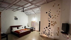 Una habitación con cama, una mesita, una silla, televisión y un diseño único en la pared.