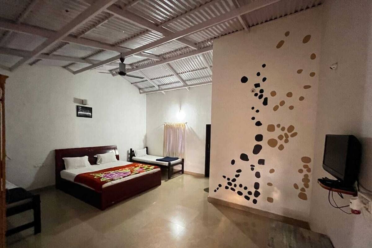 Une pièce comprenant un lit, une petite table, une chaise, un téléviseur et un mur au décor original.