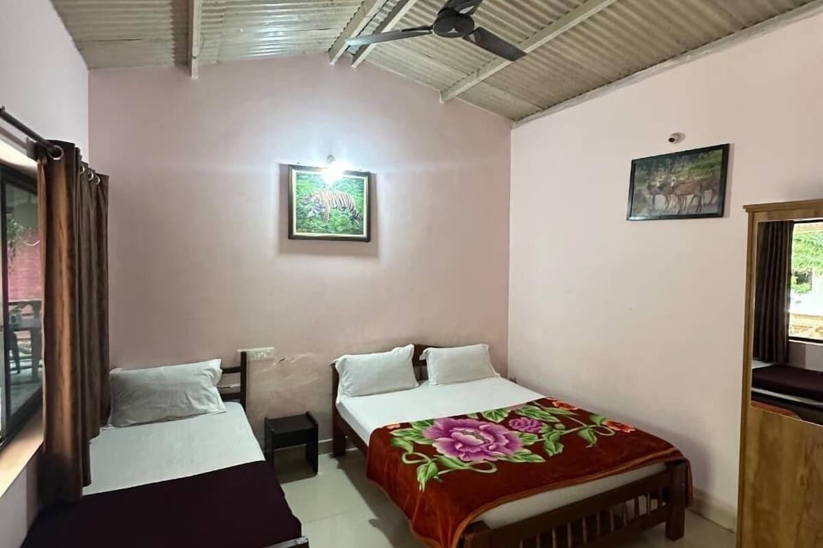 Une chambre avec deux lits, un ventilateur de plafond et une fenêtre avec des rideaux.