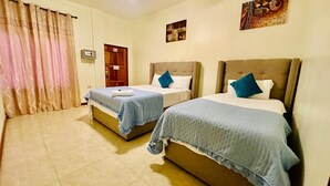Habitación de hotel con dos camas, una puerta de madera, una cortina y un reloj de pared.