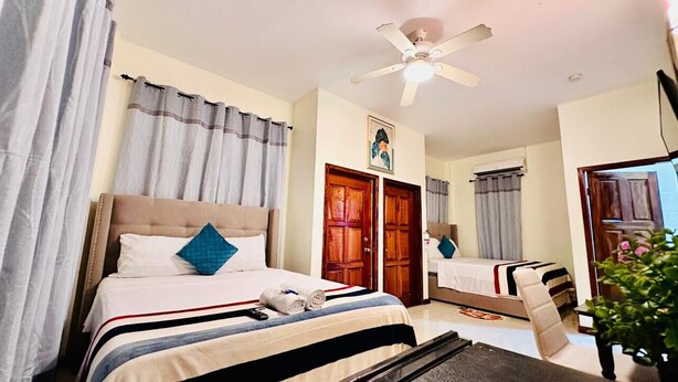 Una habitación de hotel con cama, ventilador de techo y puerta.