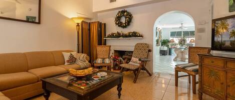 A living room with a sofa, armchairs, a coffee table, and a fireplace.