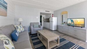 Ein modernes Wohnzimmer mit Sofa, Couchtisch, Fernseher und Küchenbereich.