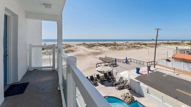 Ein Balkon mit Pool, Liegestühlen und Blick auf den Strand.