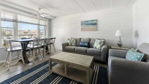 Ein Wohnzimmer mit Essbereich, einer Sofagarnitur, einem Couchtisch und einem Bild an der Wand.