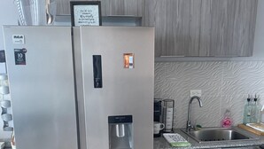 Una cocina moderna con un refrigerador de acero inoxidable, un dispensador de agua integrado y un lavamanos con grifo.