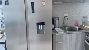 Une cuisine moderne dotée d’un réfrigérateur en acier inoxydable, d’un distributeur d’eau intégré et d’un évier avec un robinet.