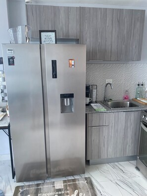Eine moderne Küche mit einem Edelstahl-Kühlschrank, einem integrierten Wasserspender und einer Spüle mit Armatur.