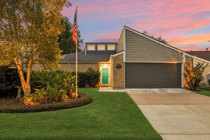 A residential house with a garage, a well-maintained lawn, and a flagpole with an American flag.