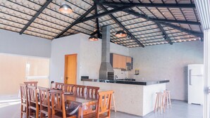Une cuisine spacieuse dotée d’un grand îlot central, de chaises en bois et d’un plafond haut avec des poutres apparentes.