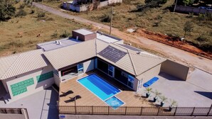Une maison moderne avec une piscine, une cour clôturée et une route en arrière-plan.