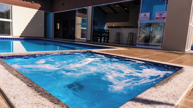 Une piscine avec un jacuzzi, entourée d’un patio aménagé avec des chaises et une table.