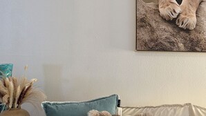 Un salon avec un canapé, un vase contenant des plantes séchées et un tableau encadré représentant un lion.