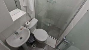 Een moderne badkamer met een douchecabine van glas, een wastafel en een toilet.