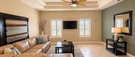 A living room with a sofa, a coffee table, a TV, and a ceiling fan.