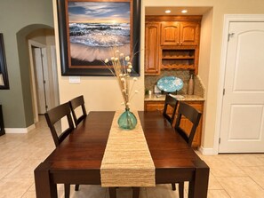 A dining area with a wooden table, chairs, a vase with dried flowers, and a framed picture on the wall. - Paradise Bay 8 - Two Bedroom Off The Beach (South Padre Island)