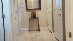 Un pasillo con suelo de baldosas, un espejo en la pared y dos puertas.